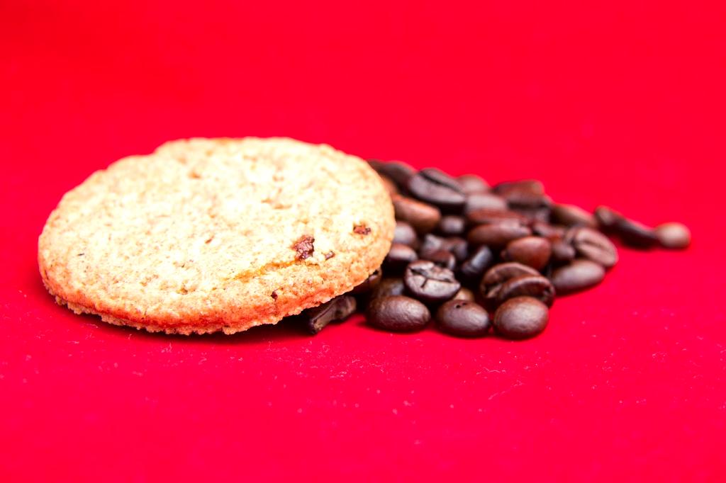 Close up of coffee cup next to cookies on wooden table